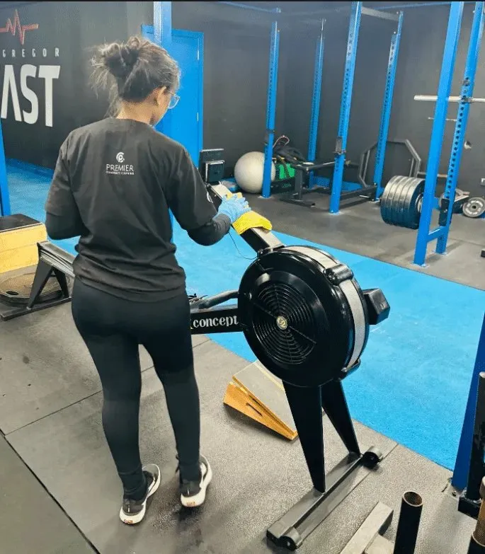 Premier cleaner disinfecting a rowing machine in a gym