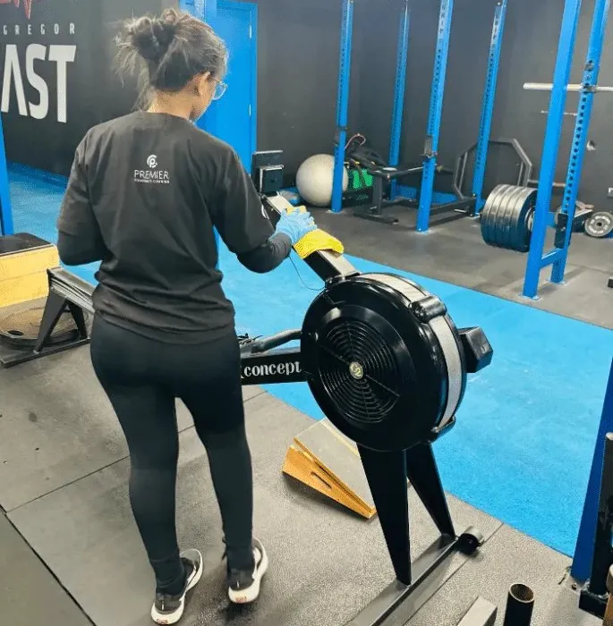 Premier cleaner disinfecting a rowing machine in a gym