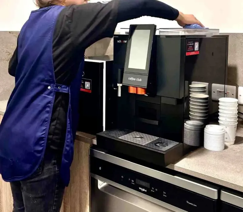 Premier cleaner cleaning a coffee machine in an office kitchen