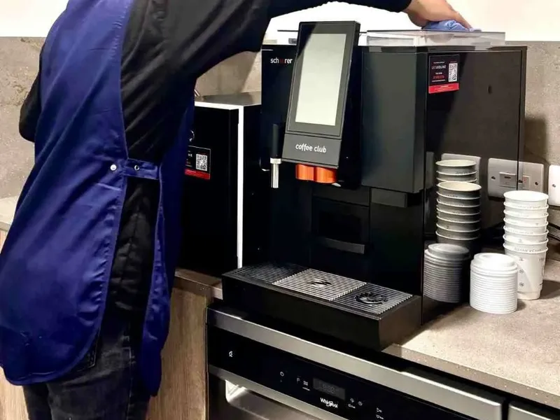 Premier cleaner cleaning a coffee machine in an office kitchen