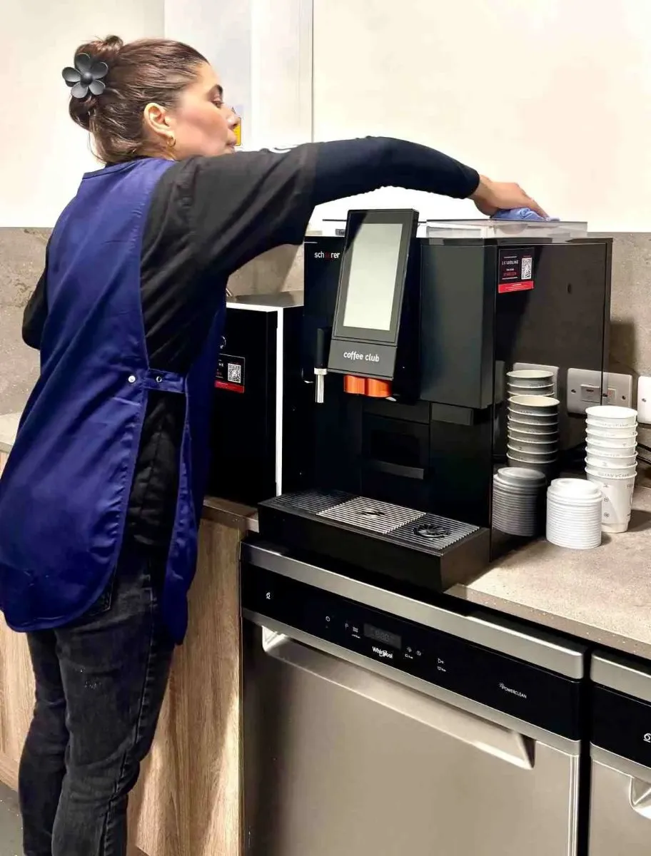 Premier cleaner cleaning a coffee machine in an office kitchen