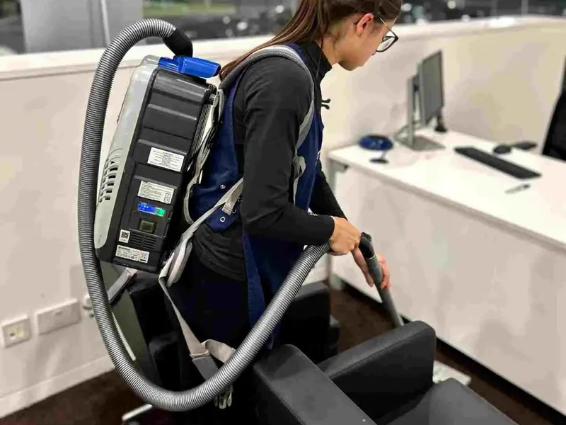 Premier cleaner using a backpack vacuum in a modern office