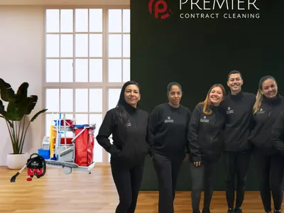 The Premier Contract Cleaning team in uniform in front of the company logo