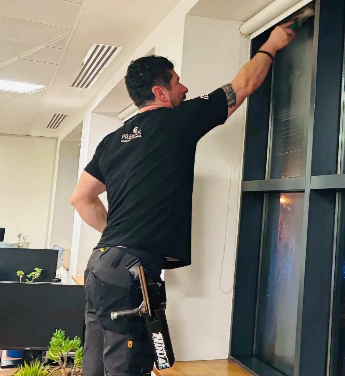 Premier cleaner cleaning a tall office window frame