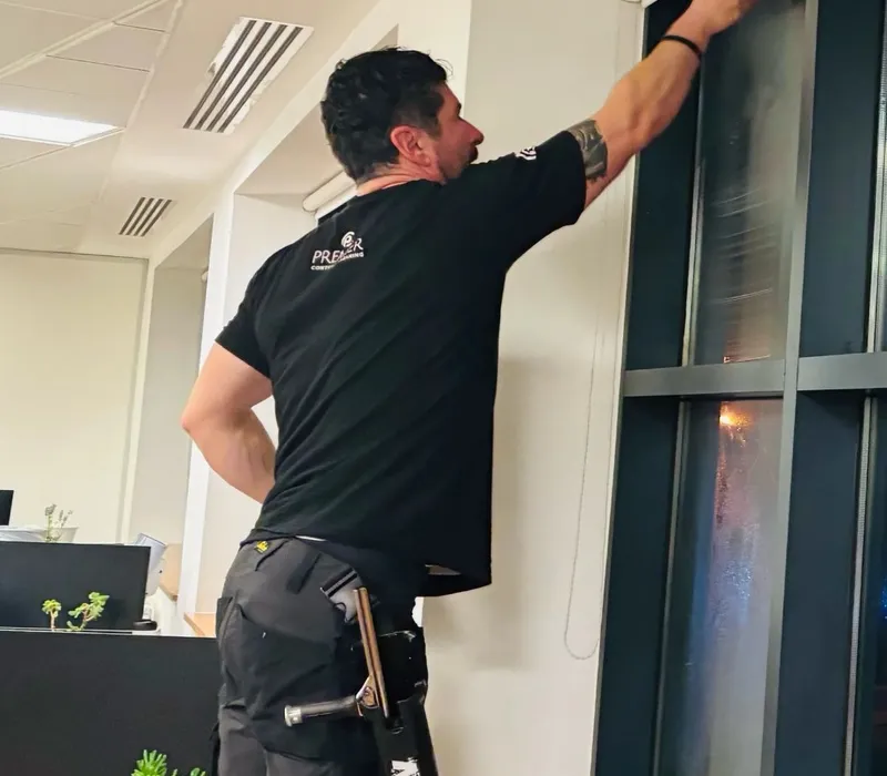 Premier cleaner cleaning a tall office window frame
